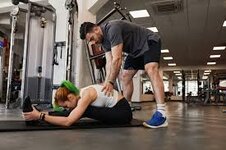 Male Personal Trainer Assisting Fit Woman in Stretching on Mat in Gym Stock  Photo - Image of posture, gymnastics: 217968108
